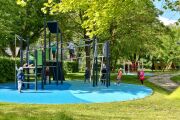 Spielplatz der Kita Kinderland, Kletterturm Rutschstangen, Balancierbalken und Kletterwand mit blauen Fallschutzmatten