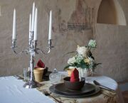 Gedeck mit Kerzenleucher, Becher, Teller, Blumen im historischen Ambiente